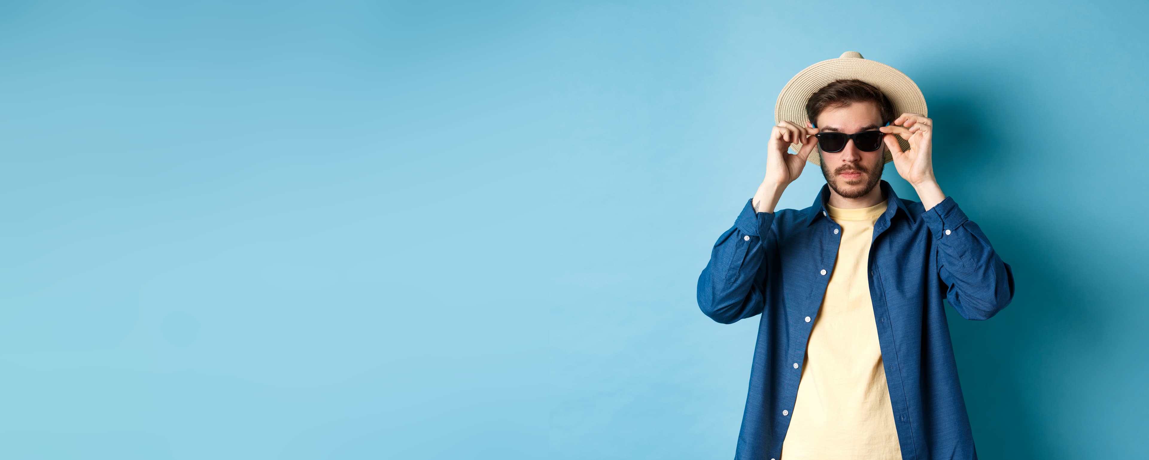 Man in a straw hat and denim shirt wearing sunglasses